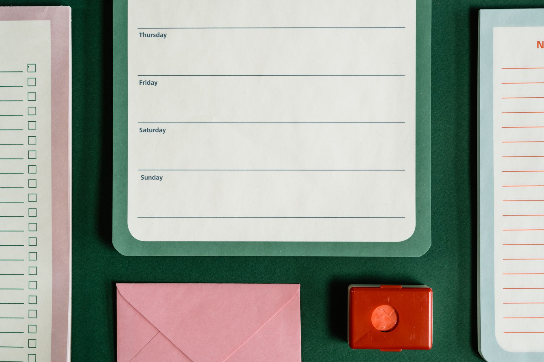 Flat lay of assorted stationery on a green surface, emphasizing organization.