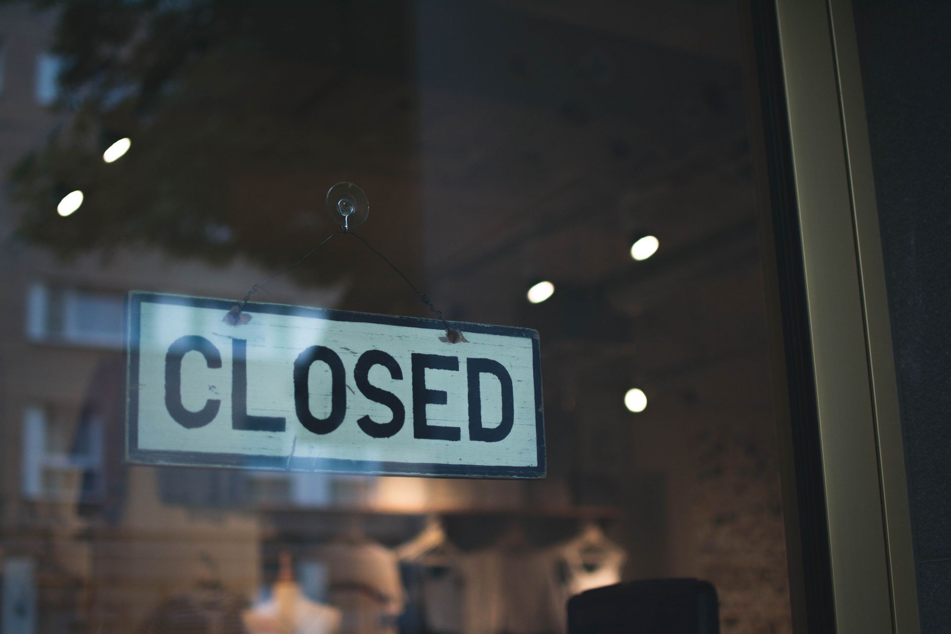 A closed sign hangs on a glass window of a modern urban storefront.