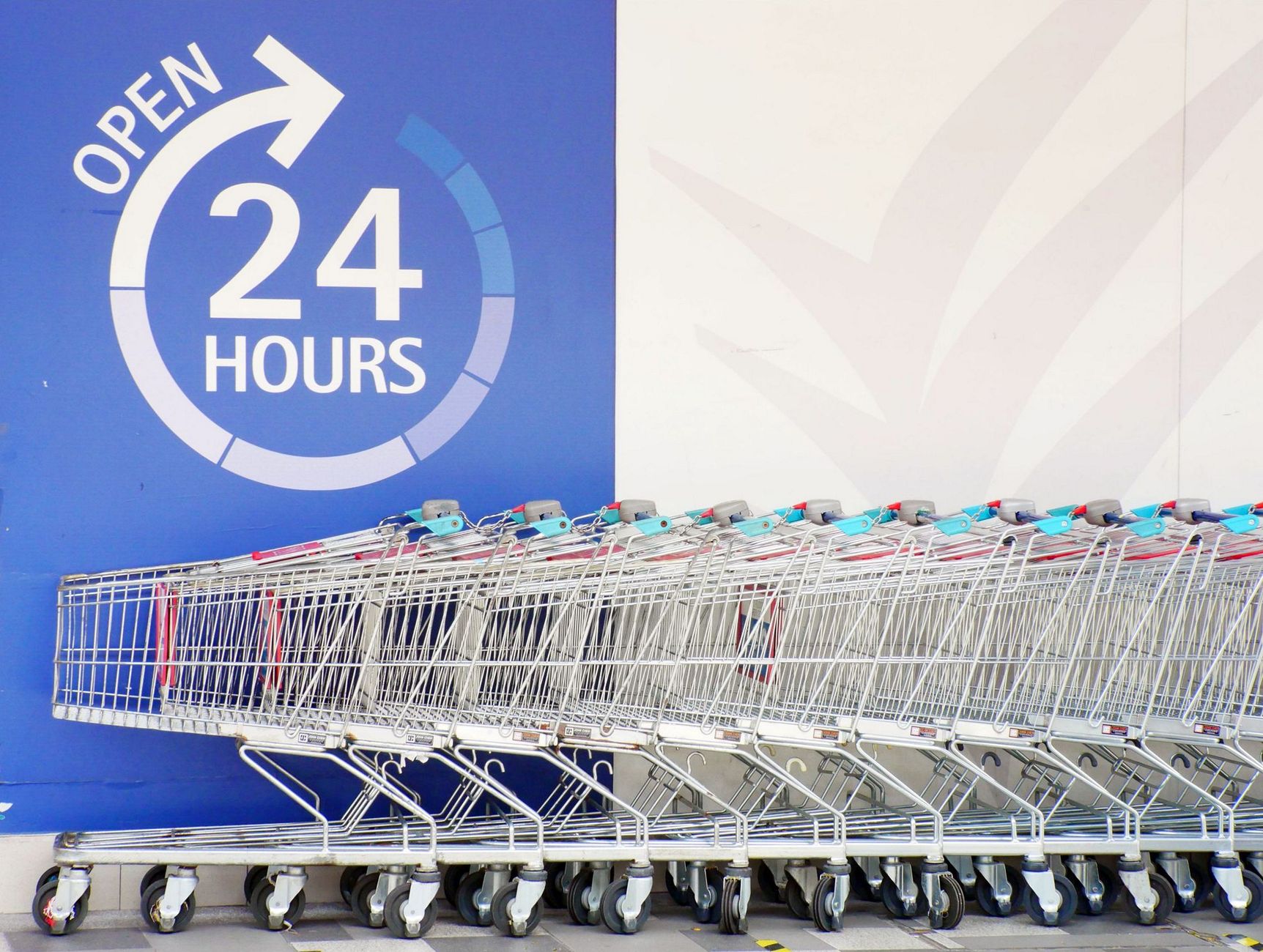 Row of shopping trolleys outside a 24-hour supermarket in Singapore, emphasizing convenience and accessibility.