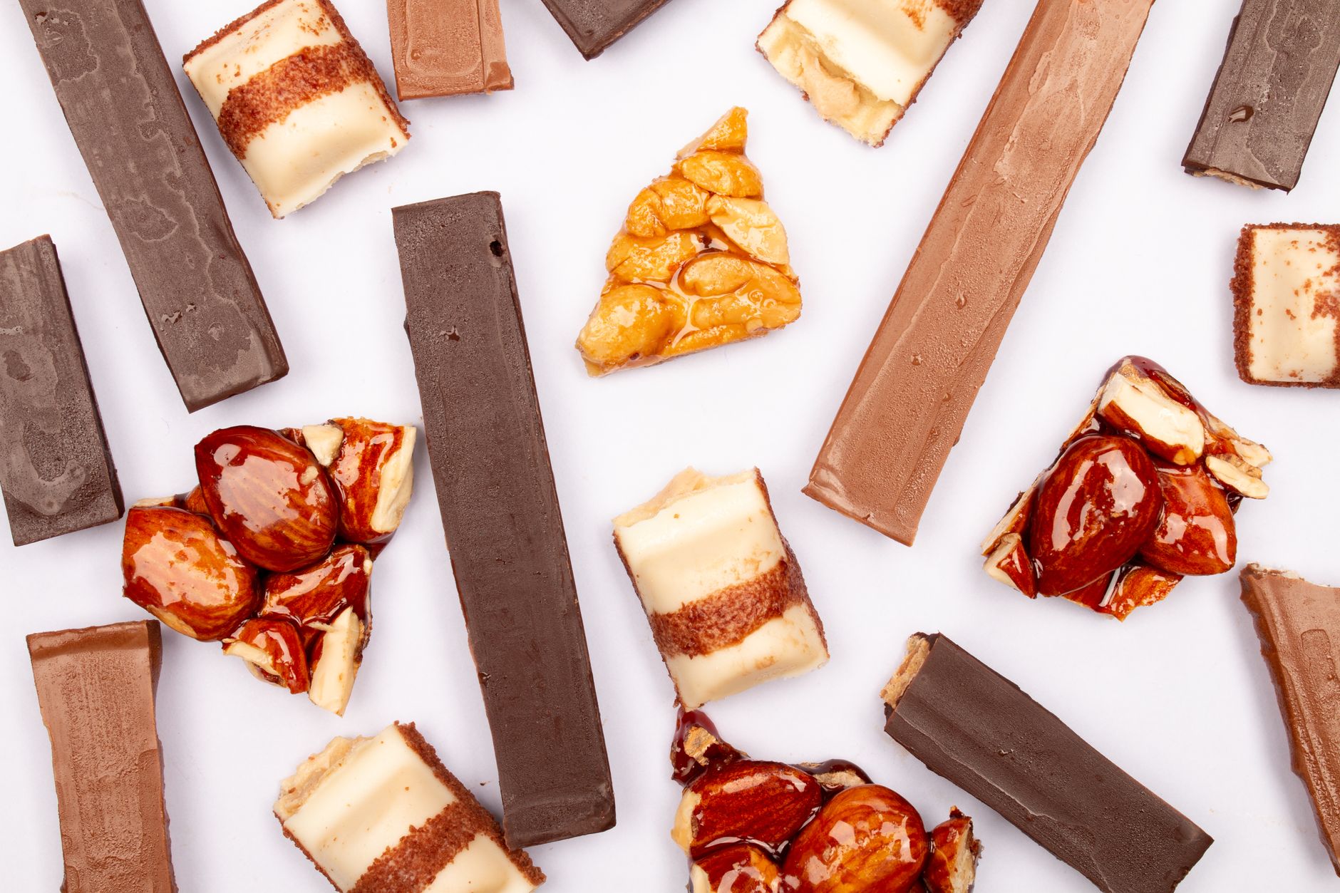 A delectable assortment of gourmet chocolate bars and sweets arranged in a flat lay on a white background.