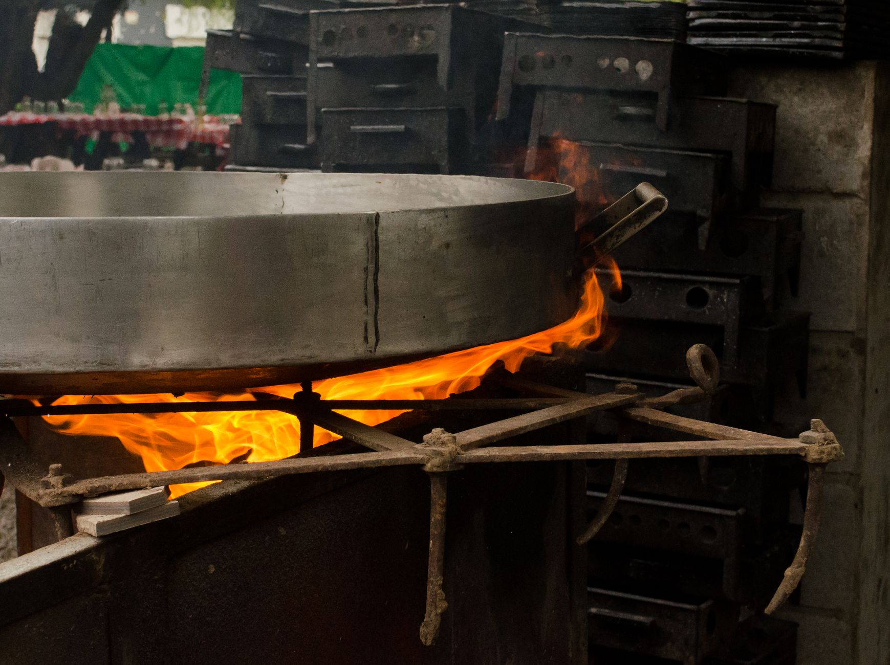 Large metal pan on open flame for outdoor cooking setup.