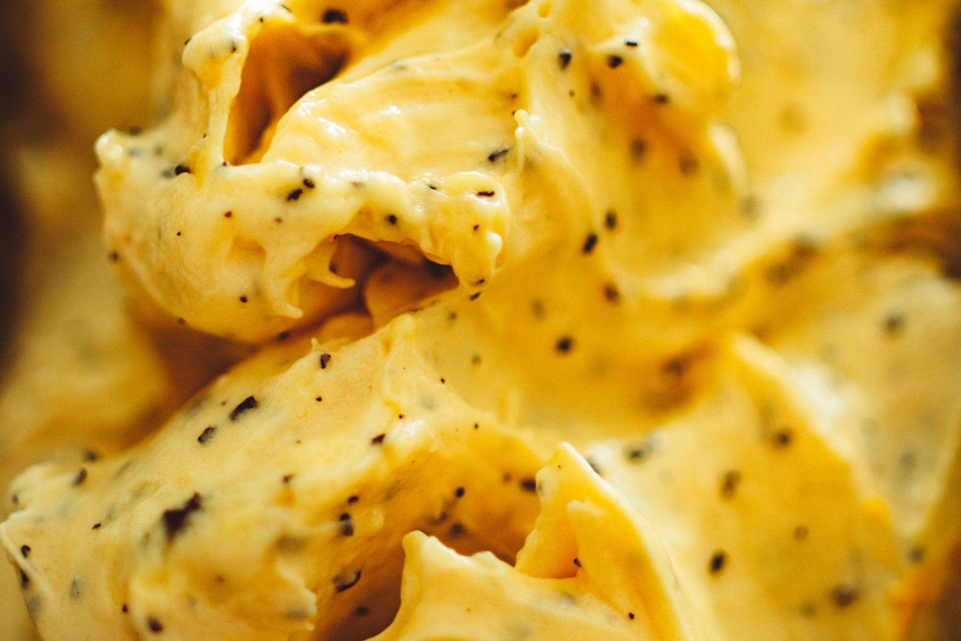 Rich and creamy yellow ice cream with visible vanilla bean specks in a close-up shot.