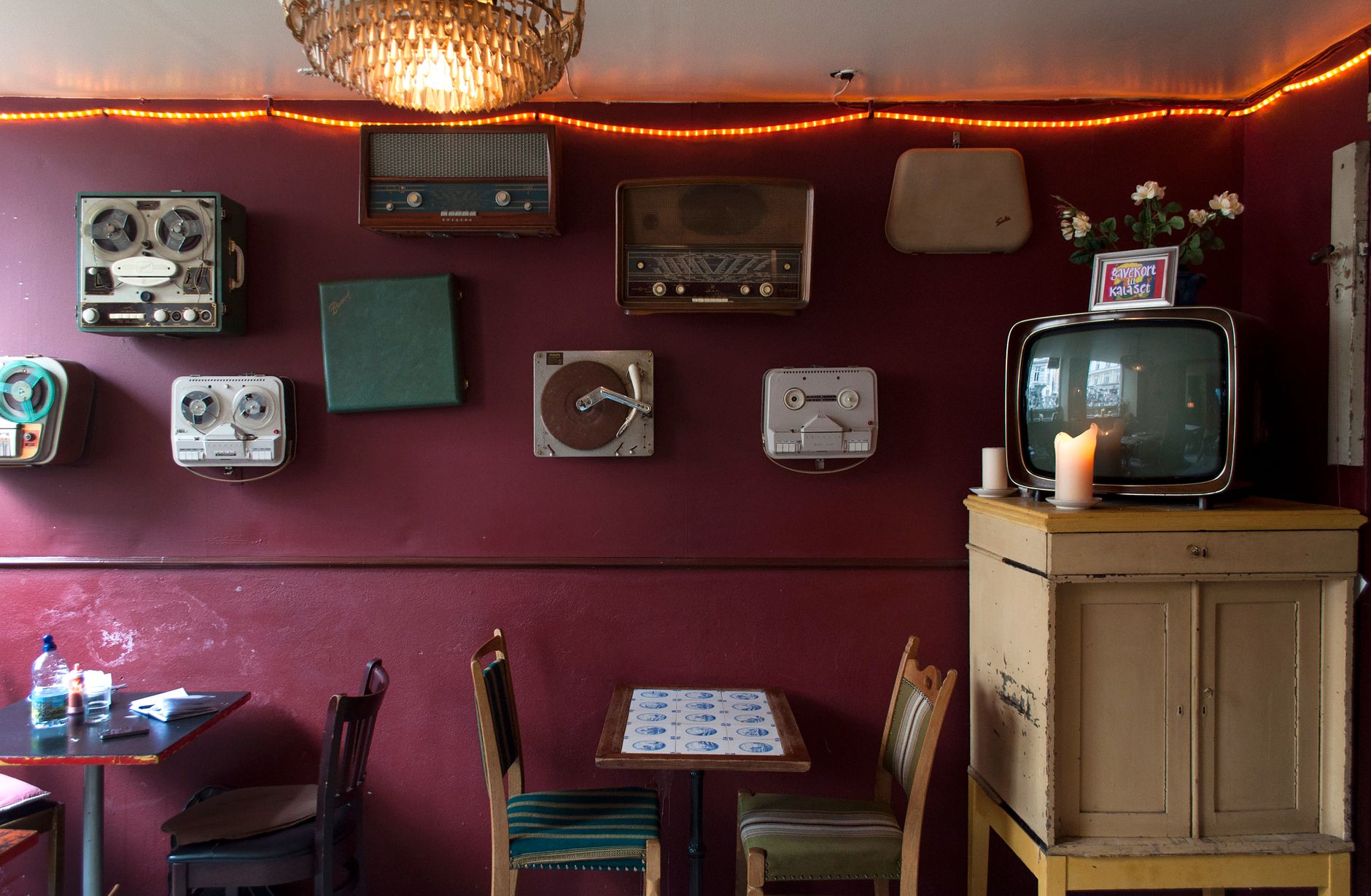 Cozy restaurant interior featuring retro TVs and old radios on a maroon wall.