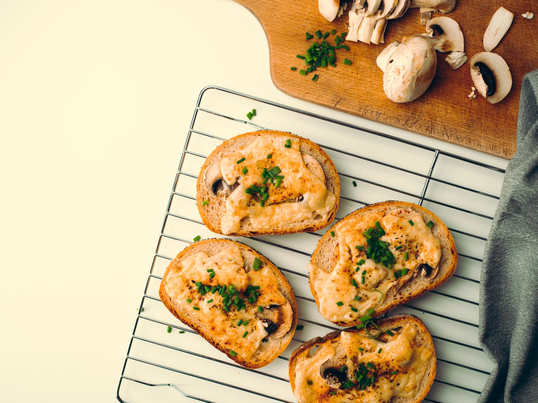 Close-up of toasted bread with mushrooms and cheese, garnished with chives, for a delicious breakfast.