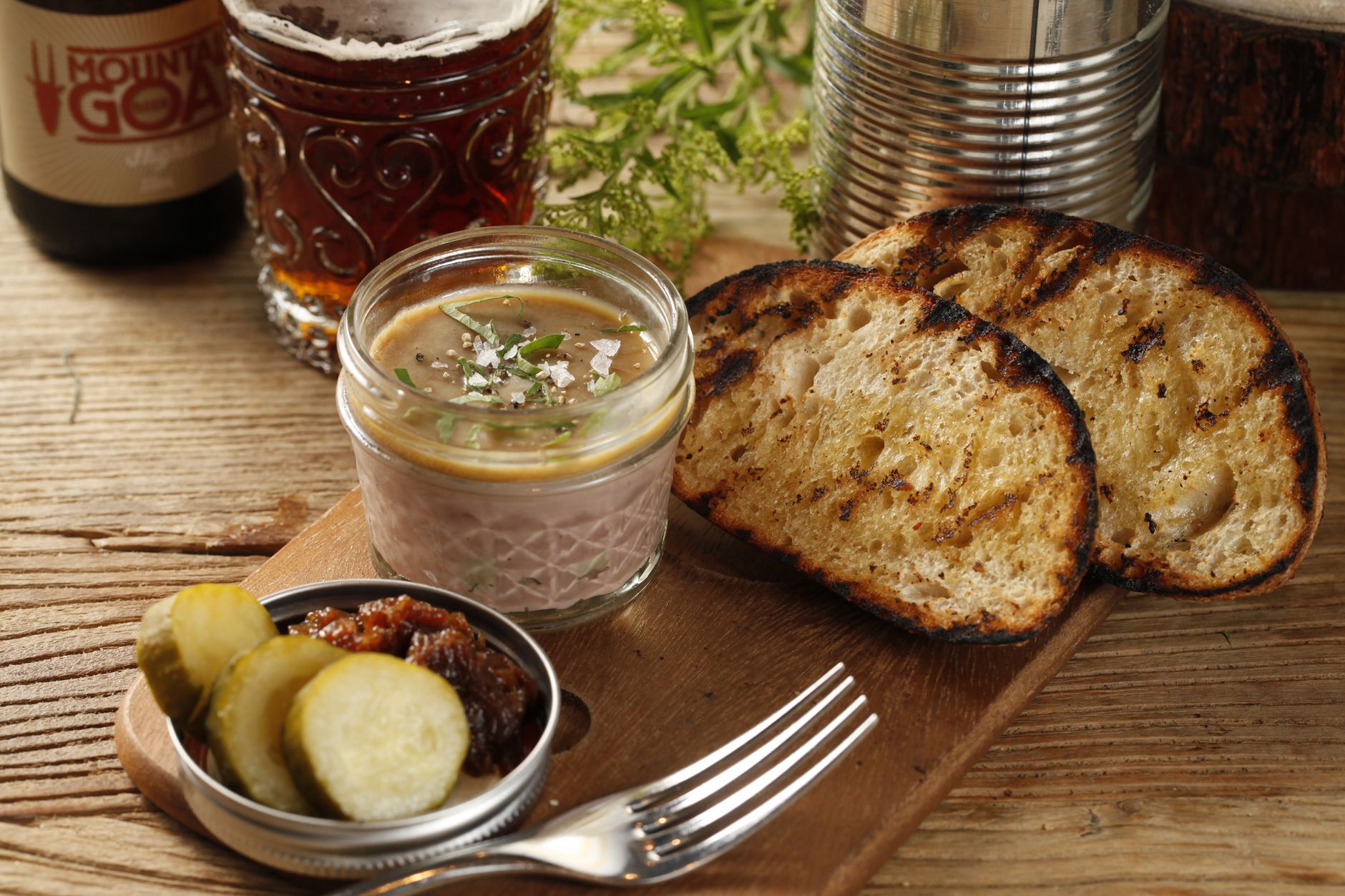 Delicious pate served with pickles and grilled bread on a wooden table, perfect for food enthusiasts.