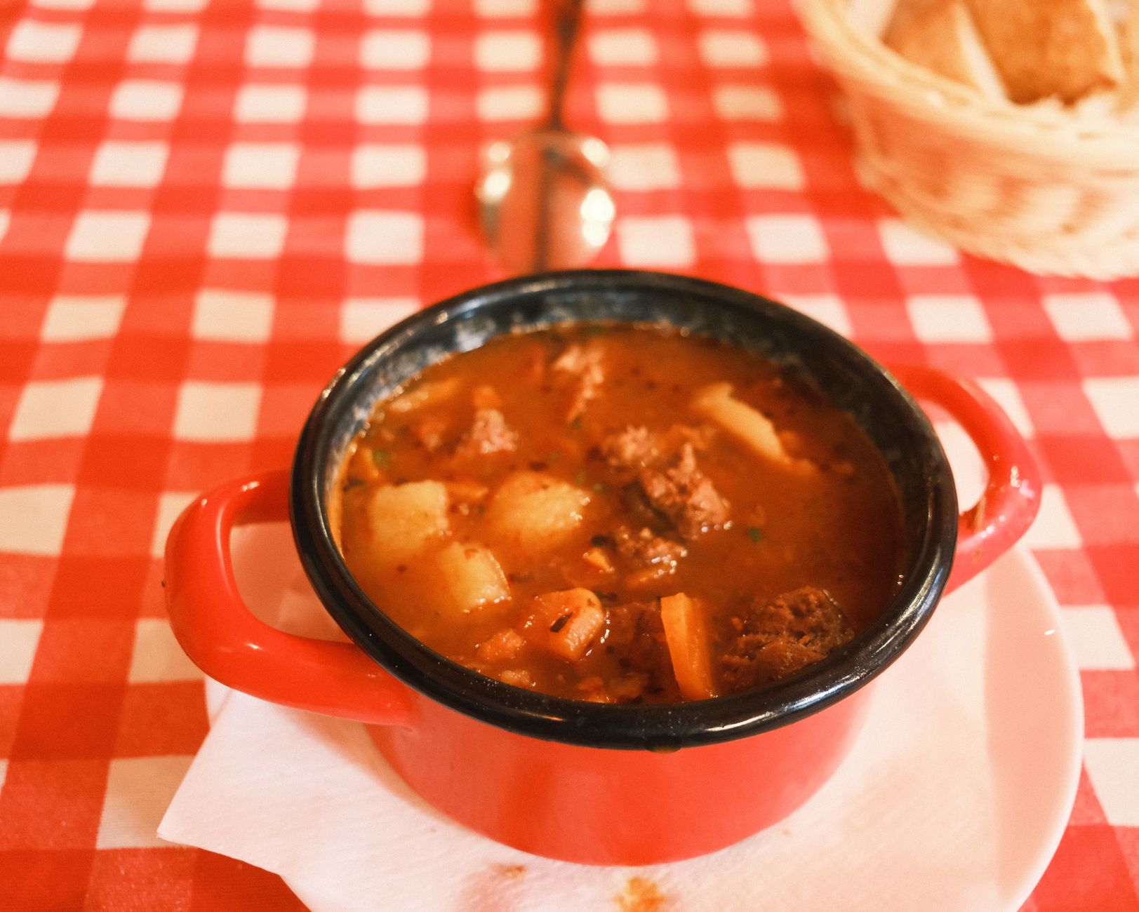 Delicious Hungarian goulash served in a red pot on a checkered tablecloth in Budapest.