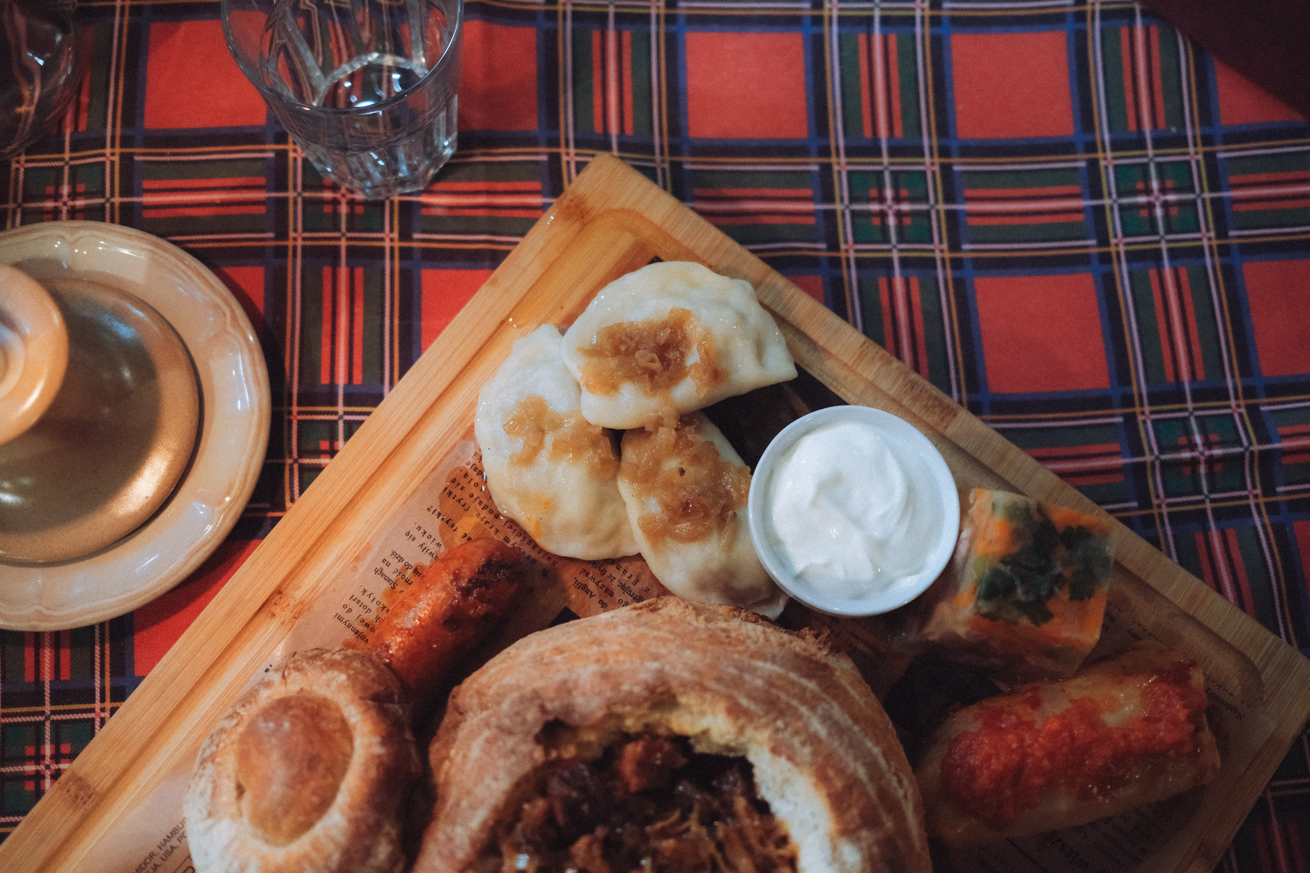 Delicious Polish dishes with dumplings, soup in bread, and cabbage rolls on a wooden board.