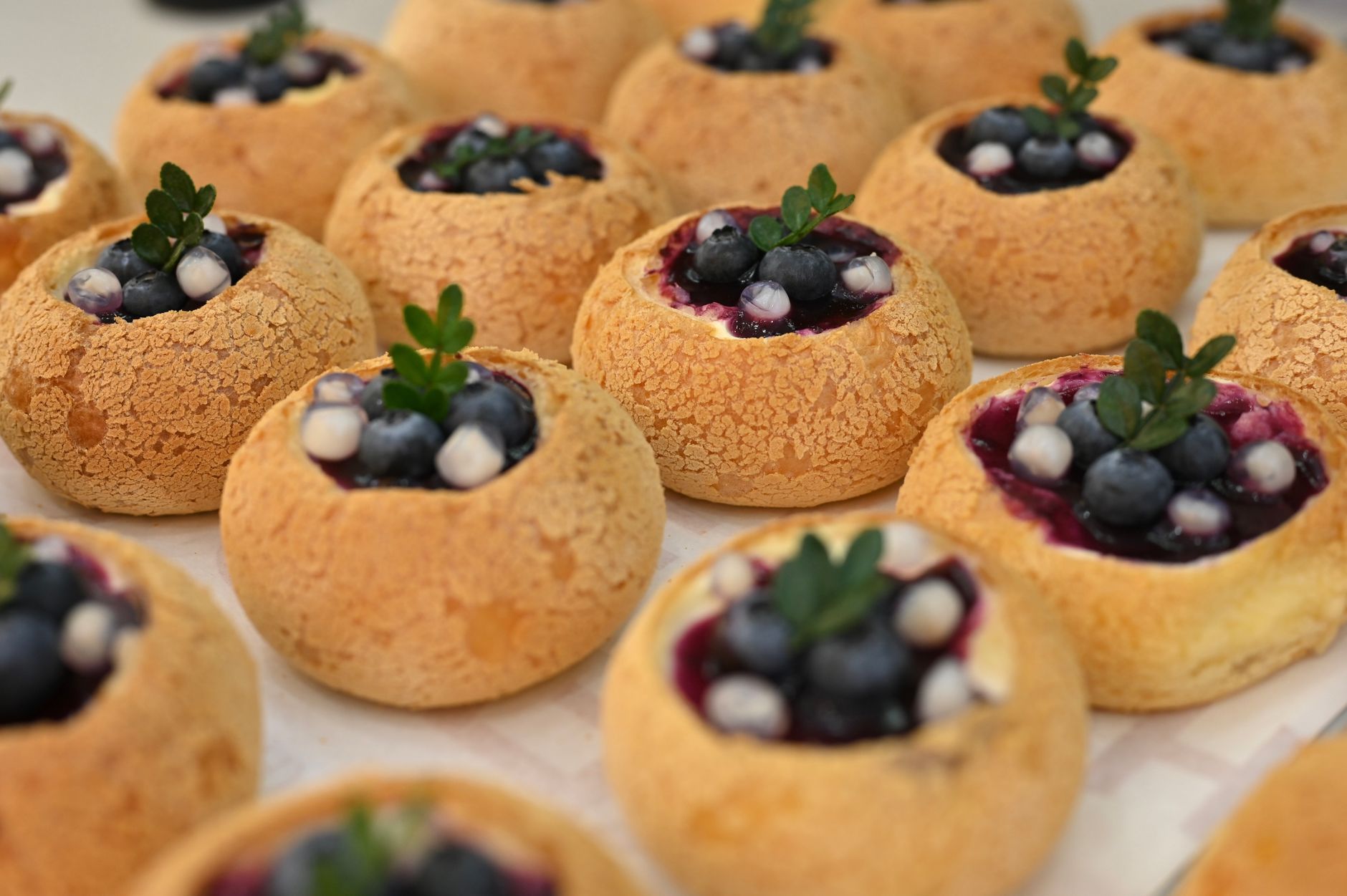 Freshly baked pastries filled with blueberries and cream garnished with mint leaves.