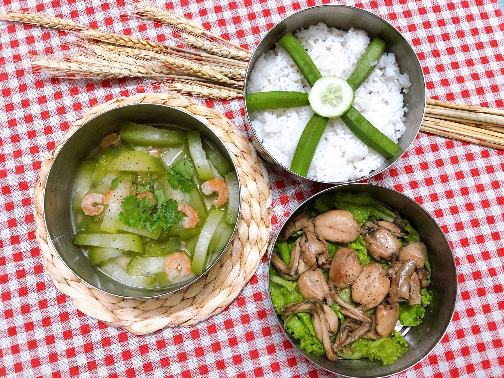 A delicious traditional Vietnamese meal featuring rice, shrimp, and frog legs served on a red checkered cloth.