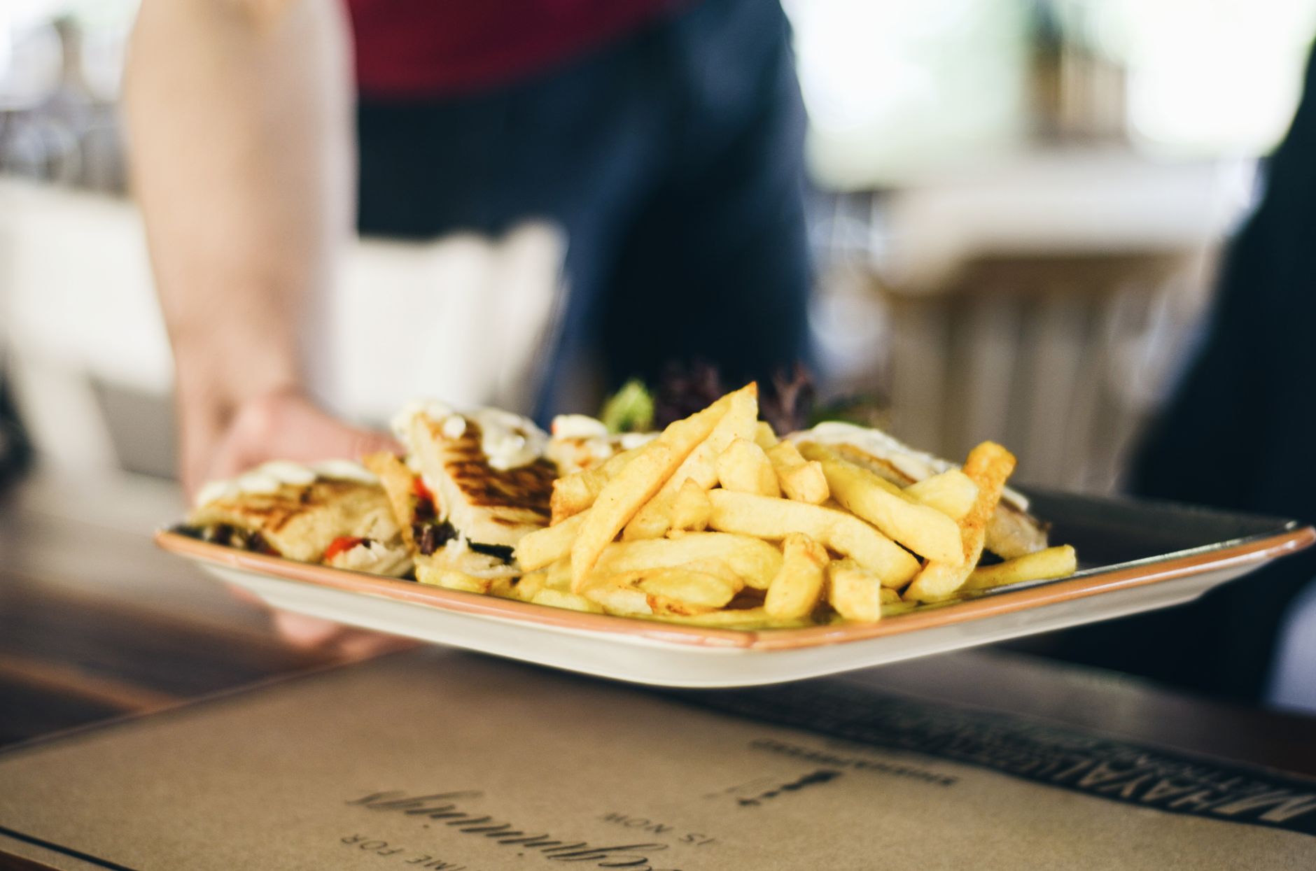 Close-up of delicious french fries and sandwich served on a plate indoors.