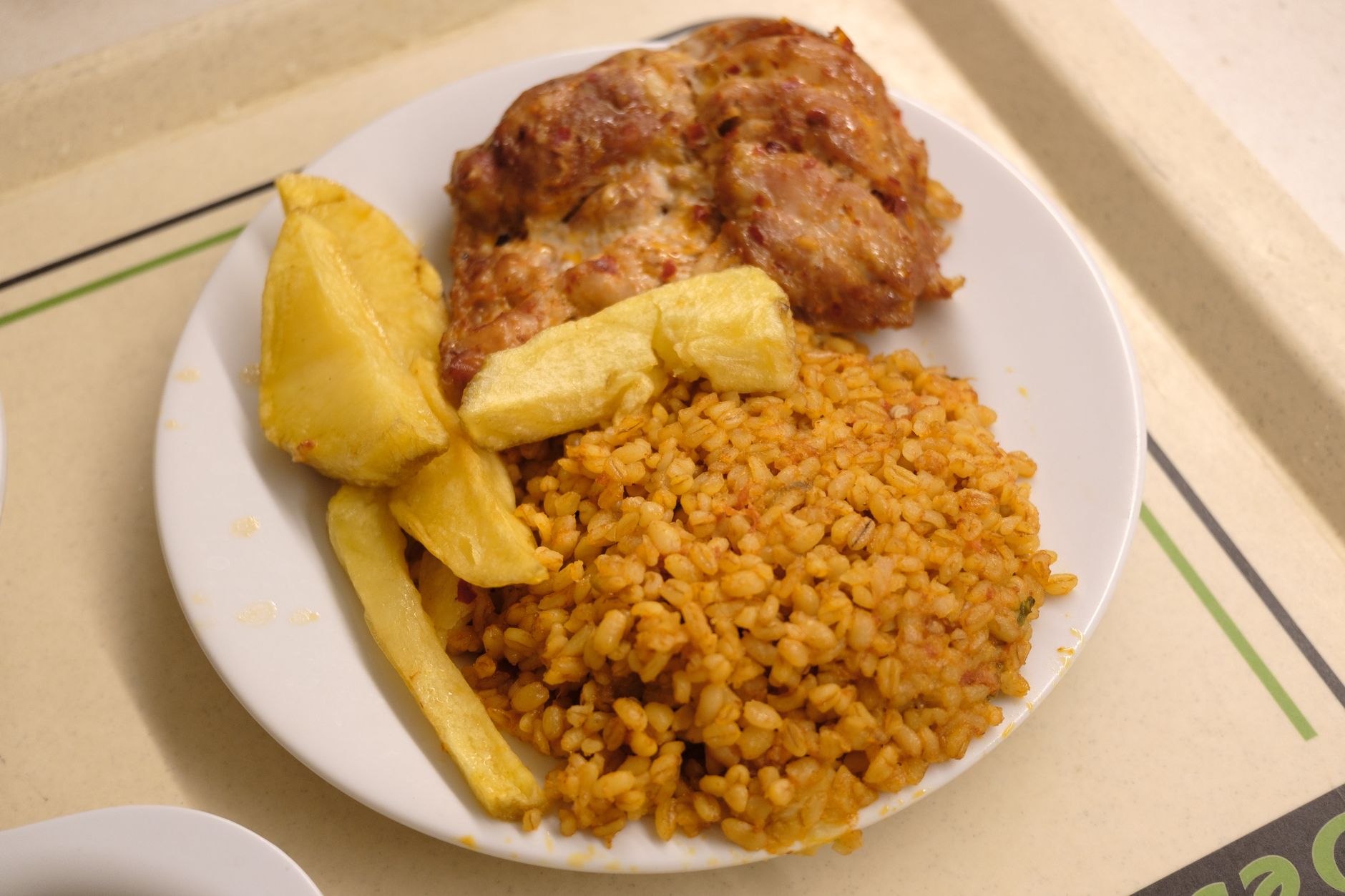 Plate of fried potatoes, seasoned rice, and grilled meat on a tray.