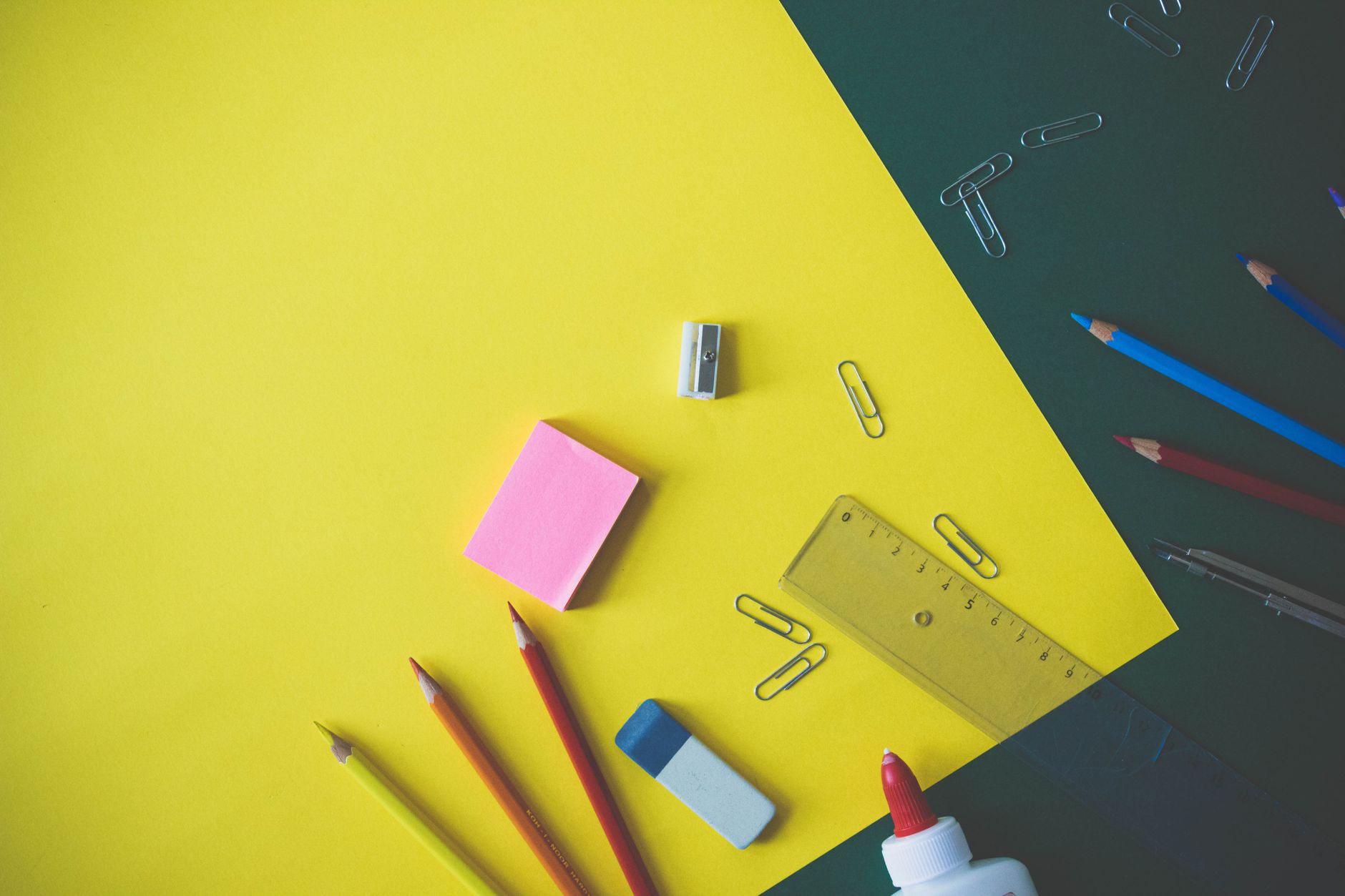 Flat lay of colorful school supplies arranged on a vibrant yellow background, ideal for back-to-school themes.