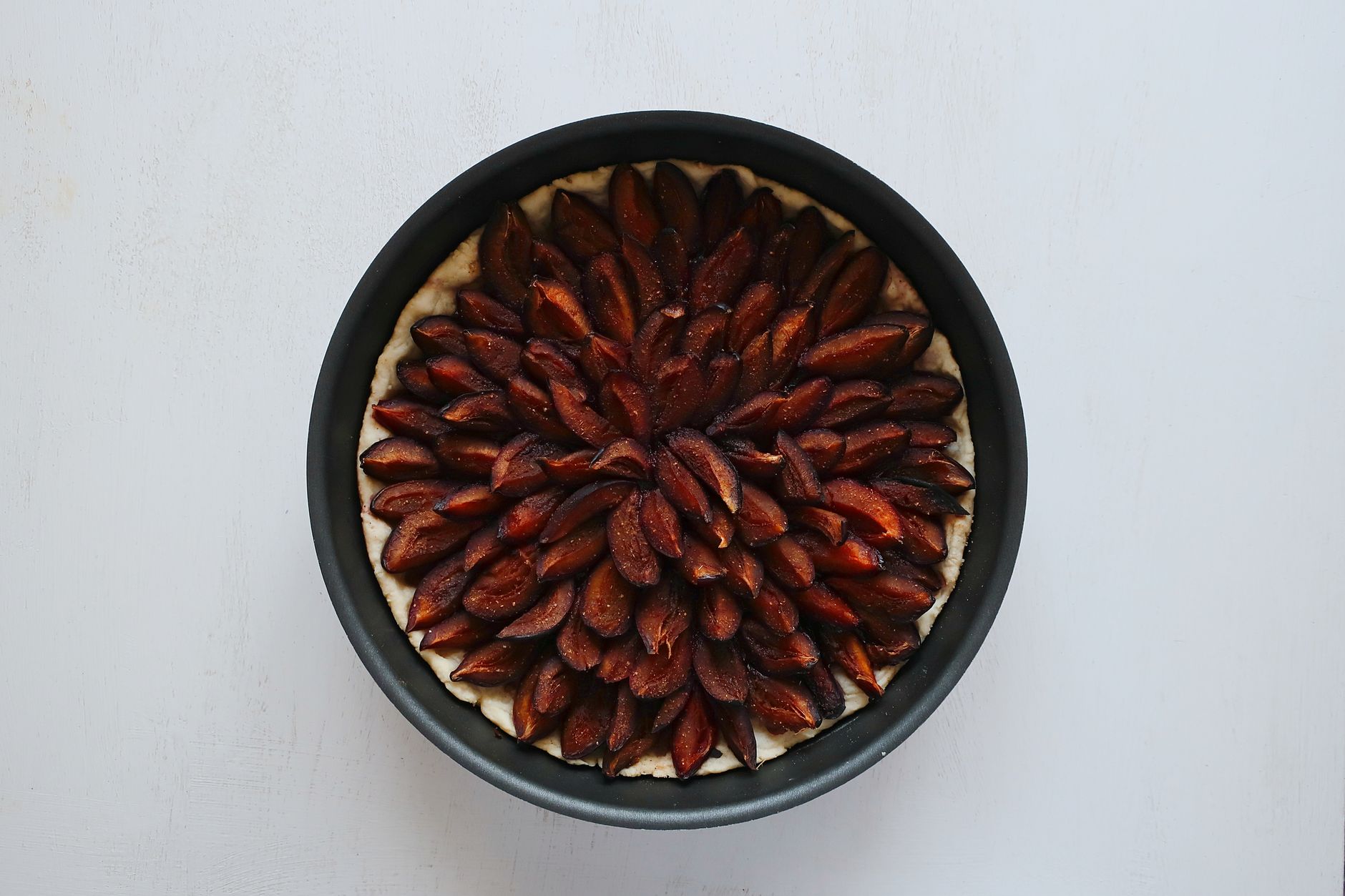 A close-up flatlay of a homemade plum tart with arranged prune plums.