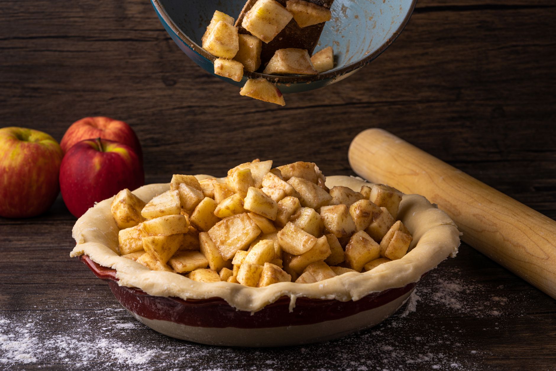 Fresh apple pie preparation with cinnamon-spiced apples in a dough crust, ready for baking.