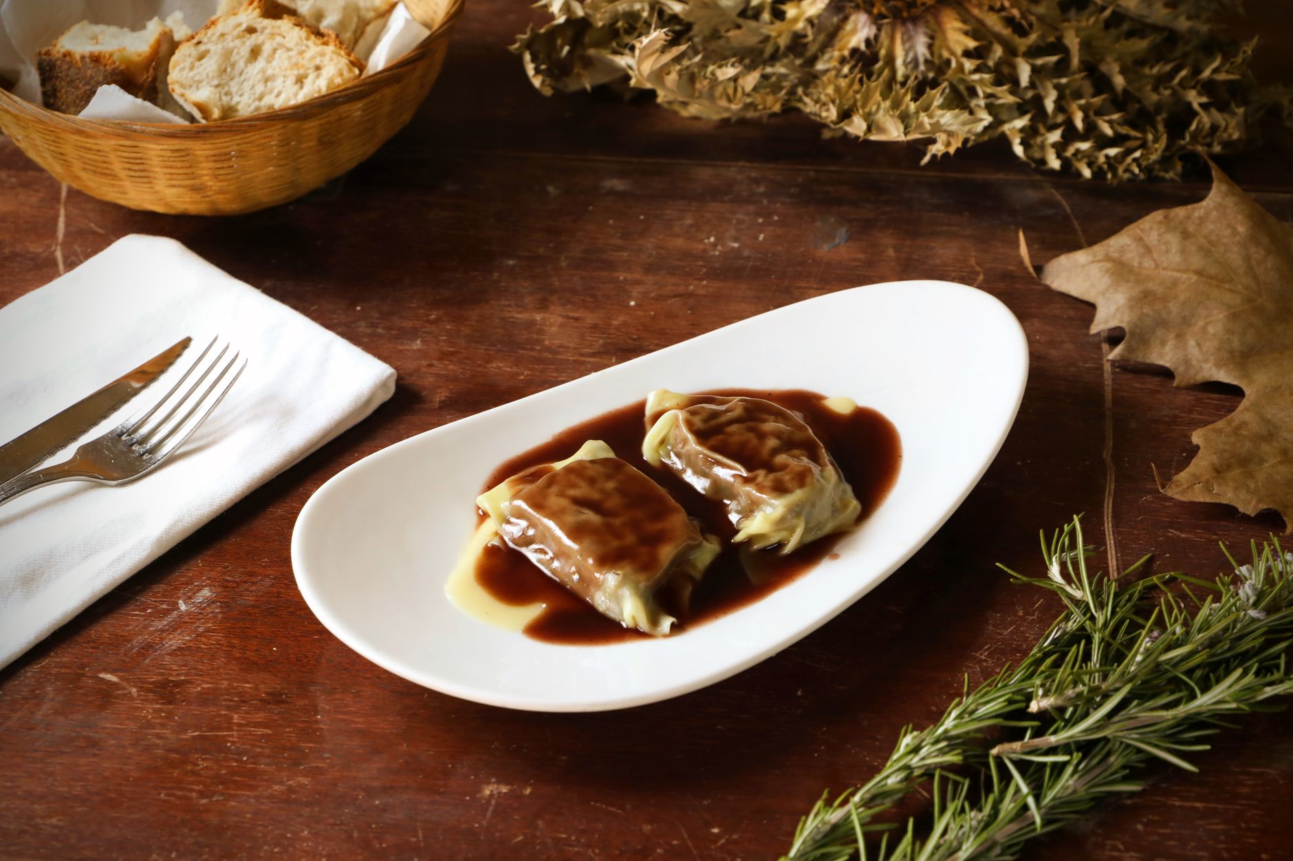 Appetizing stuffed cabbage rolls drizzled with rich sauce on a rustic table.