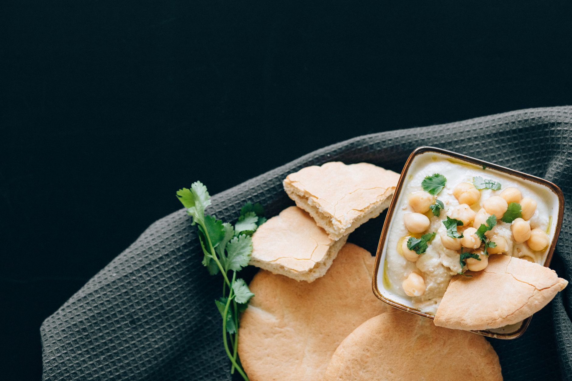 Delicious homemade hummus with chickpeas and pita bread, served on a textured surface.