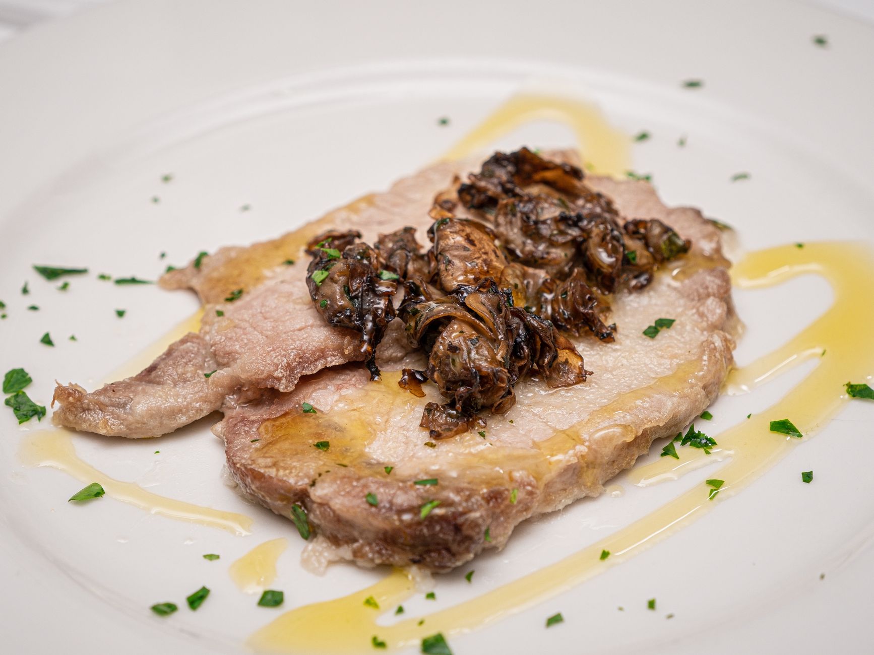 Sliced pork garnished with sautéed mushrooms and herbs, presenting a gourmet culinary delight.