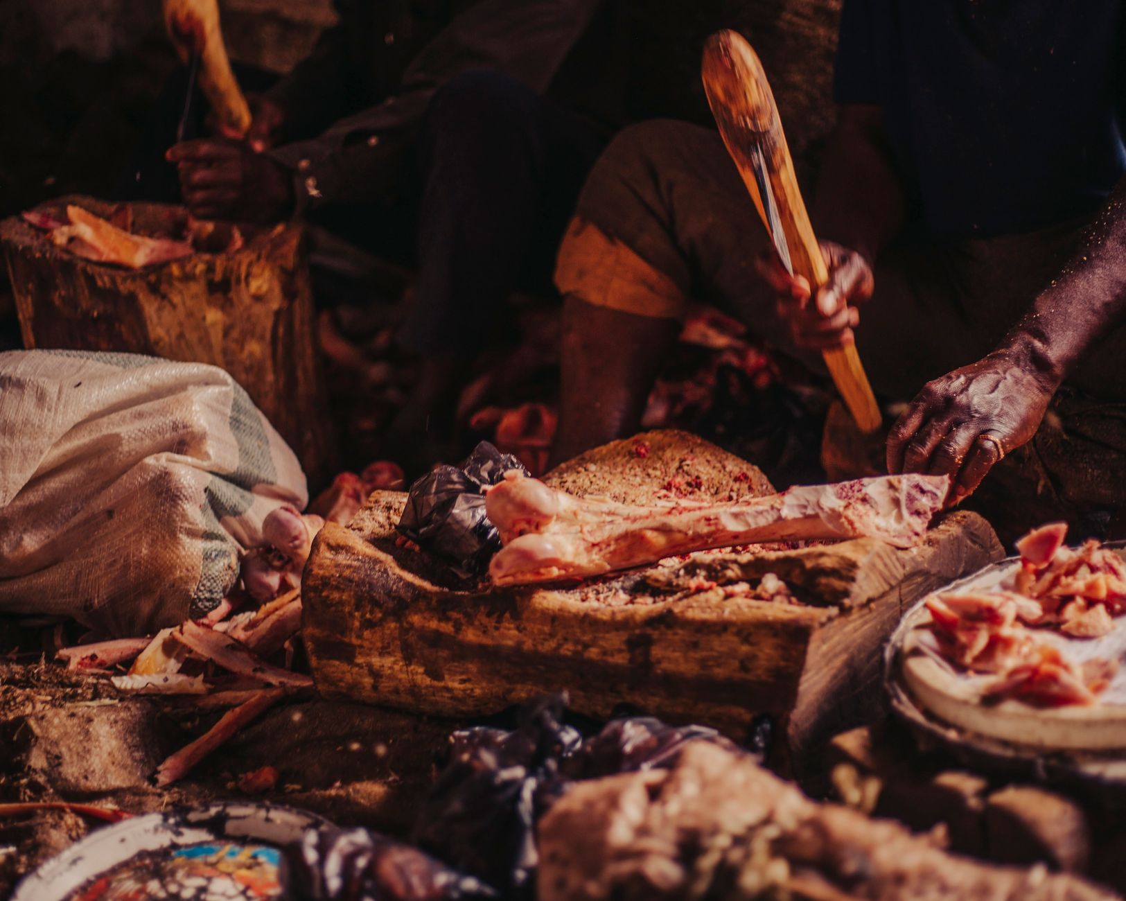 Hands-on butchering process using traditional wooden tools in a rustic setting.
