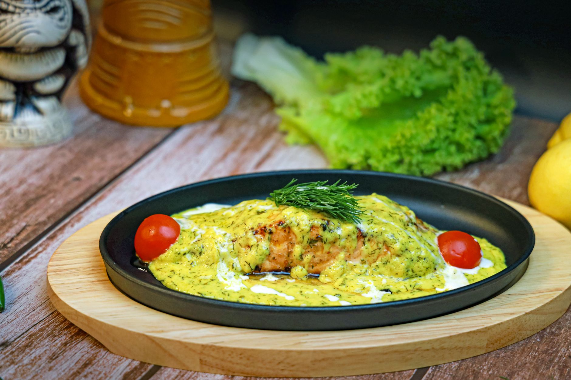 Appetizing salmon dish with dill cream sauce garnished with cherry tomatoes and fresh herbs.