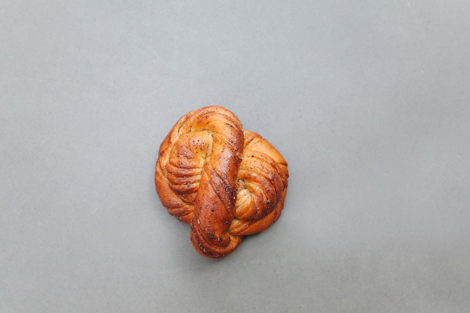 Close-up of a fresh homemade Swedish cardamom bun on a neutral background.