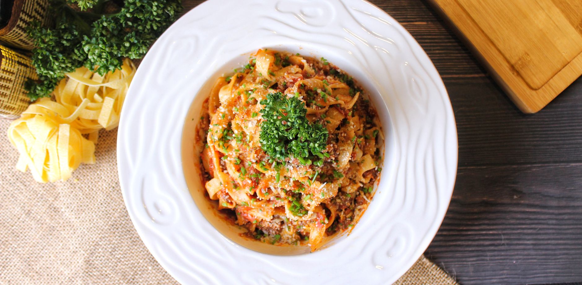 A beautifully plated bowl of homemade pasta garnished with fresh parsley and Parmesan cheese.