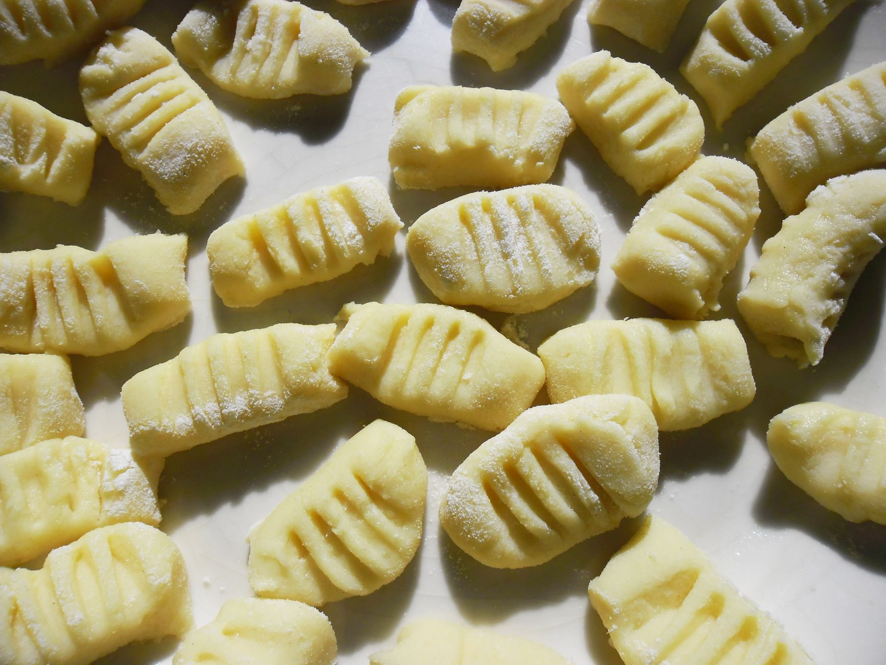 Close-up of fresh homemade gnocchi pasta arranged on a flour-dusted surface, ready for cooking.